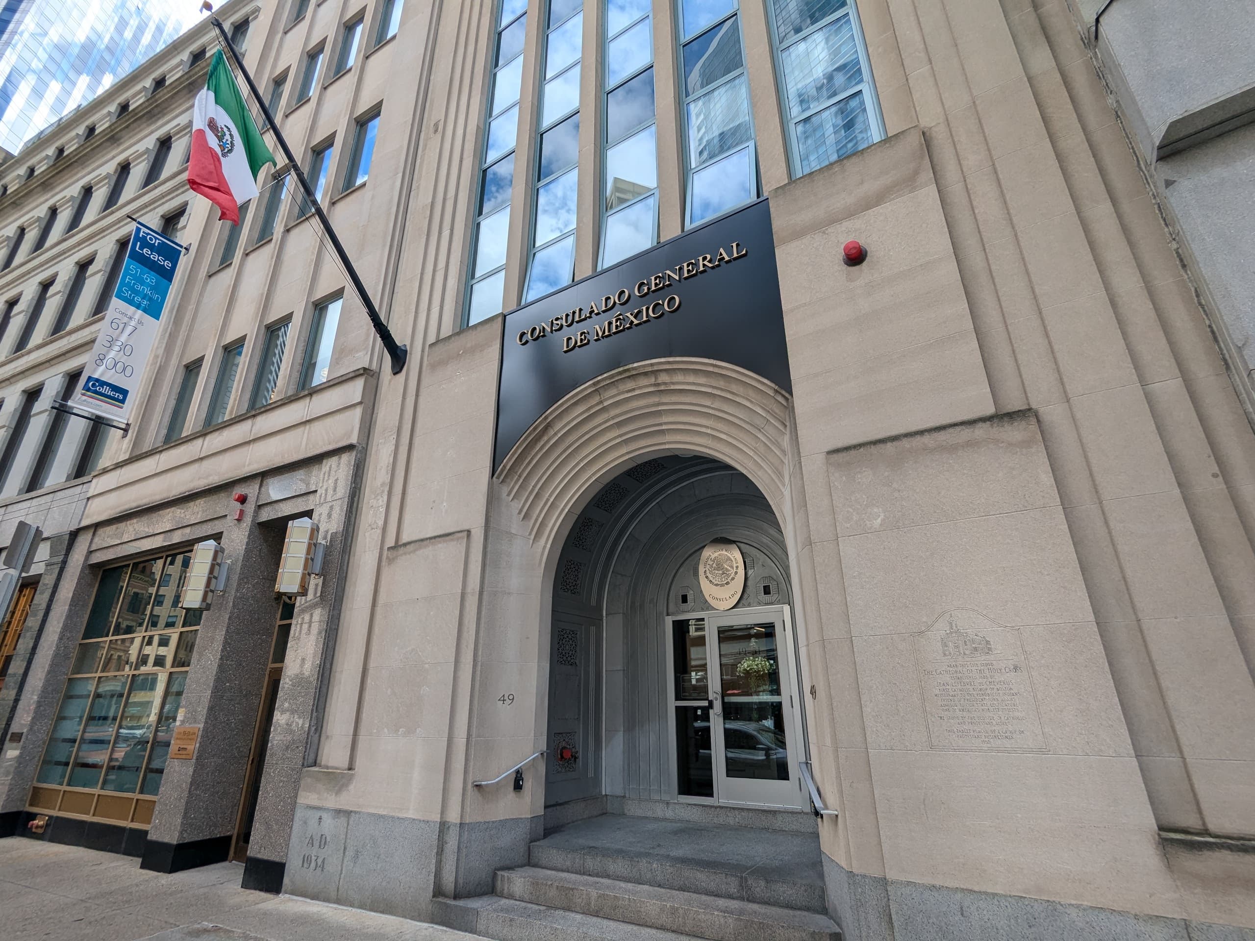 Fachada del Consulado General de México en Boston con la bandera mexicana ondeando frente al edificio.